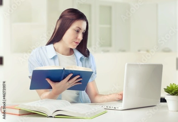 Fototapeta Caucasian female student working from home writing, sitting next to books