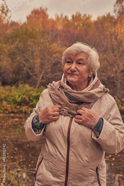 Fototapeta Portrait of a woman 65 years old against the background of autumn trees.