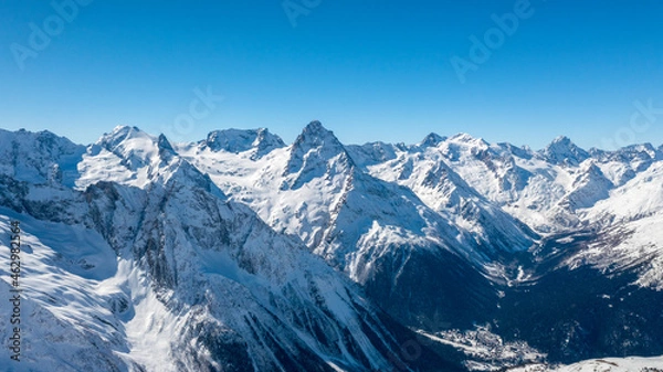 Fototapeta Caucasus Mountains, Panoramic view of the ski slope with the mountains Belalakaya, Sofrudzhu and Sulakhat on the horizon in winter day. Dombai ski resort, Western Caucasus, Karachai-Cherkess, Russia.