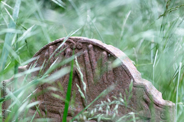 Fototapeta Graves and tombstones in the old cemetery in the park in the fog and rain in the morning. Hands carved into the tombstone.