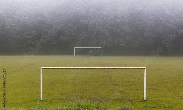 Fototapeta The girl or women runs on the field between the goals in the grass in the fog and rain in the park. Horizontal header banner copy space blog background