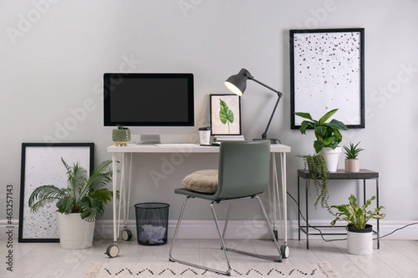 Fototapeta Comfortable workplace with modern computer and houseplants in room. Interior design