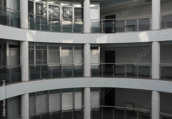 Fototapeta Photo in a building of several gray floors with glass balconies and white columns