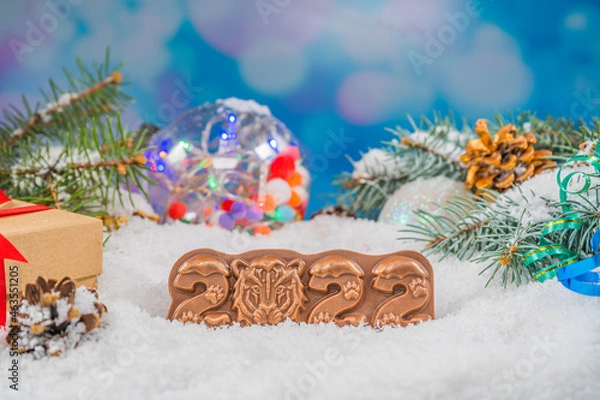 Fototapeta Christmas chocolate figure on snow. chocolate figurine shape 2022. New Year's composition