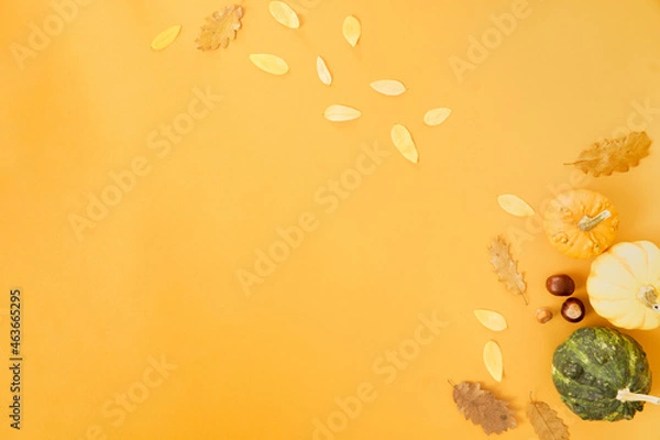 Obraz Autumn concept. Foliage with pumpkins and nuts on orange background. Minimal composition with copy space for thanksgiving and halloween.
