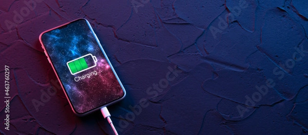 Fototapeta Mobile smart phone charge charging device on dark neon red and blue color background. Icon battery and charging progress lighting on screen.smartphones connected to power source.Low battery