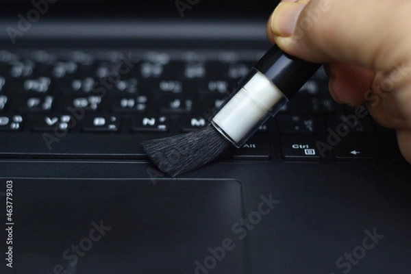 Fototapeta Cleaning the keyboard with a dust brush