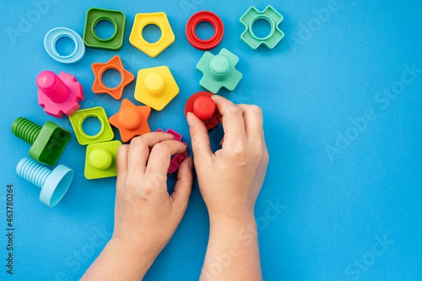 Obraz hands collect educational constructor for children, nuts and bolts in the form of geometric shapes