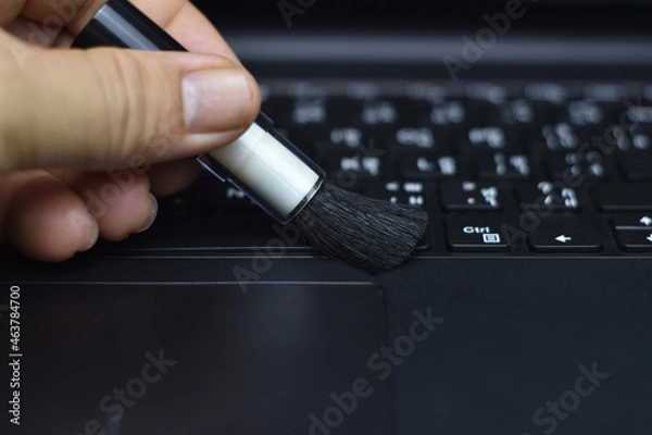 Fototapeta Cleaning the keyboard with a dust brush