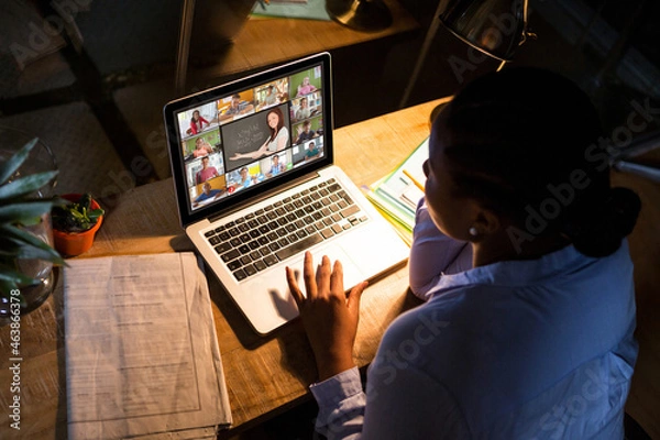 Fototapeta African american woman using laptop for video call, with diverse high school pupils on screen