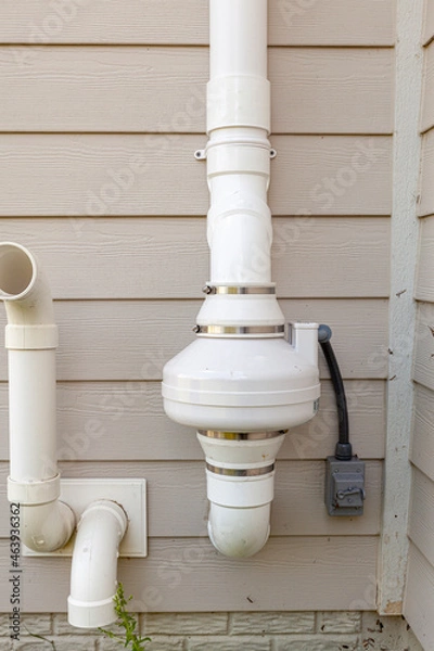 Fototapeta PVC pipes attached to the electrical motor of a residential radon mitigation system. TIt sucks radon rich basement ground air and removes it from the top of the house. Also helps with humidity