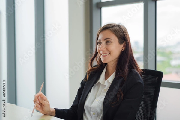 Fototapeta Smart business woman in formal suit outfit working about company task in front of computer with happy and smile in modern office workplace.