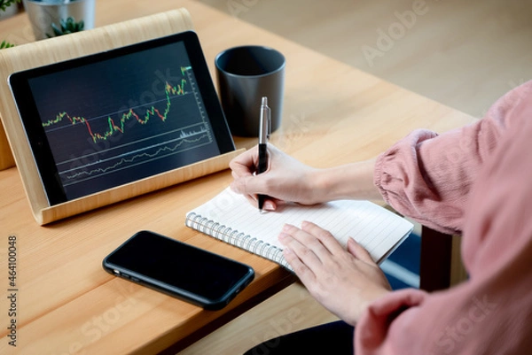 Fototapeta stock trade at home.  Close up hand of person learning and analyzing the chart of stock market via application