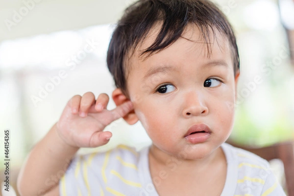 Obraz Little asian toddler baby boy has earache when insects inside outdoor baby infant boy hands touching in ear and pain.deaf kid.Flu and sick.Clean up earwax.Accident in kid with ear.Condition and clean.