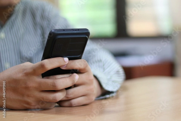 Fototapeta Person using a social media marketing concept on mobile phone with notification icons of like, message, comment and star above smartphone screen.
