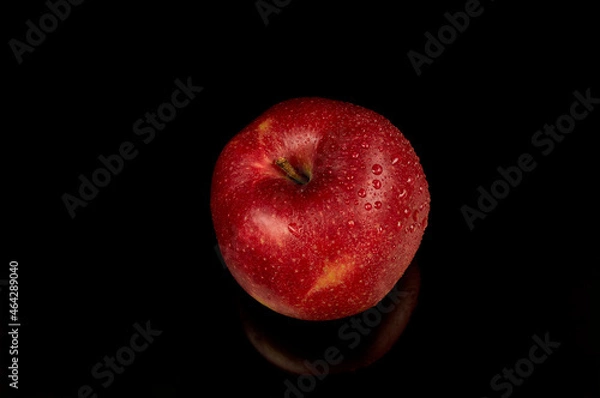 Fototapeta Wet red apple on a black background. Water drops on a beautiful fresh apple.