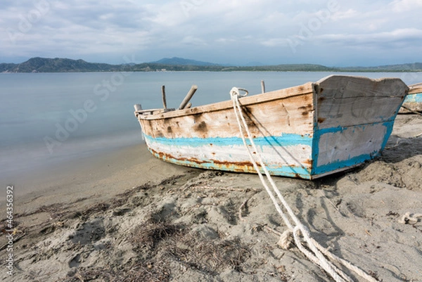 Fototapeta Dramatic long exposure image of a old weathered wooden fishing boat tied to the Caribbean coast in the Dominican Republic.