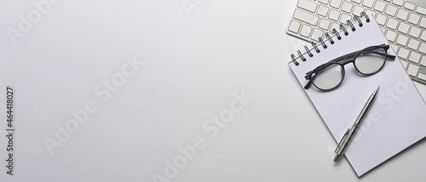 Fototapeta Empty notepad, eyeglasses, keyboard and pen on white office desk. Copy space.