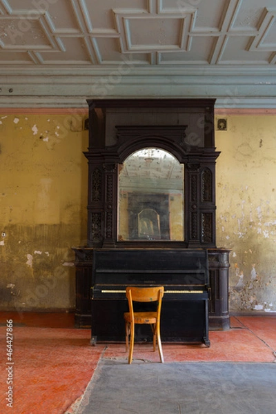 Fototapeta A beautiful antique mirror in a wooden frame and an old black piano in the interior of the ceremonial hall in Sharovsky castle, Ukraine