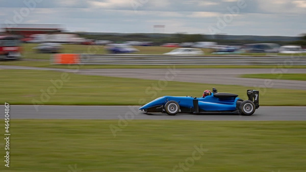 Fototapeta A panning shot of a racing car as it circuits a track.