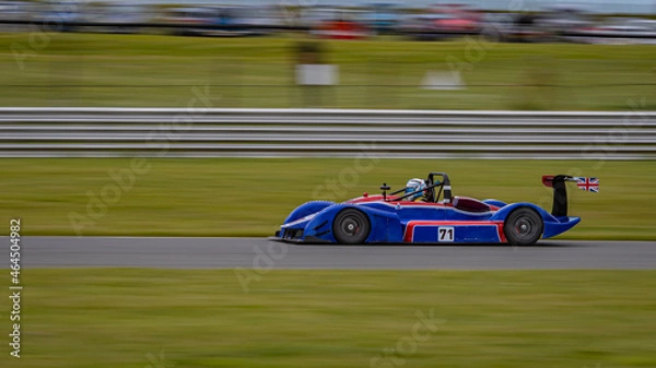 Fototapeta A panning shot of a racing car as it circuits a track.