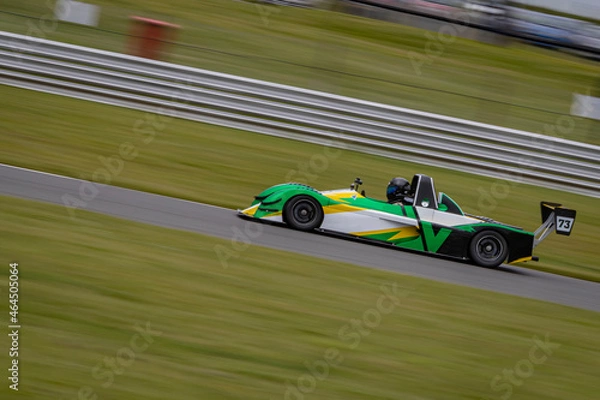 Fototapeta A panning shot of a racing car as it circuits a track.