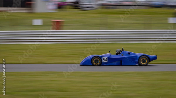 Fototapeta A panning shot of a racing car as it circuits a track.