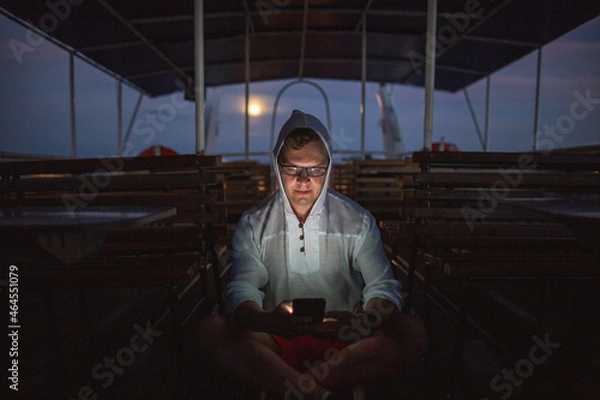 Fototapeta Dramatic night portrait of a man with a phone on an empty pleasure ship