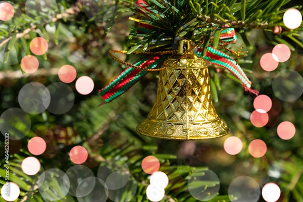 Fototapeta Christmas background. Bokeh. A Christmas bell hangs on a spruce branch.