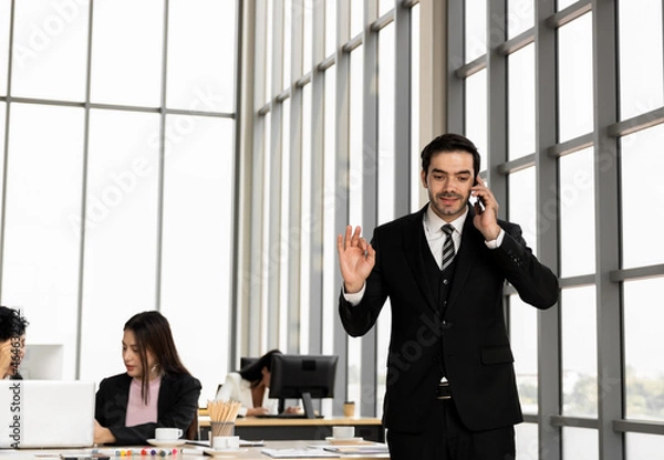 Fototapeta Young businessman talking on the phone. Discuss business and financial contract deals. Communication and conversation with stress. Reach of business agreement affects the operations of the company.