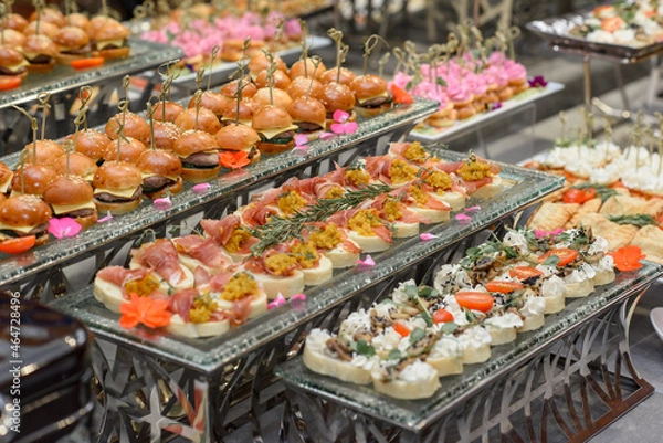 Fototapeta A set of canapes and snack at a banquet with white table. Slices of tomato, olive, cheese, bread and fish on food stand