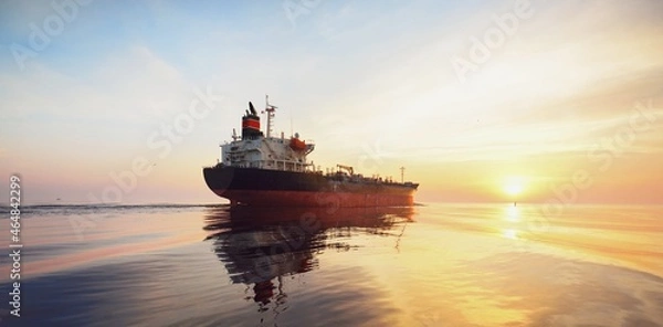 Obraz Large cargo ship sailing in the Baltic sea at sunset. Soft golden sunlight. Concept seascape. Panoramic view from the sailing boat. Freight transportation, nautical vessel, logistics