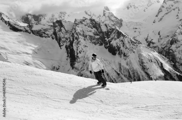 Fototapeta Snowboarder downhill on ski slope in high snowy mountains. Black and white toned