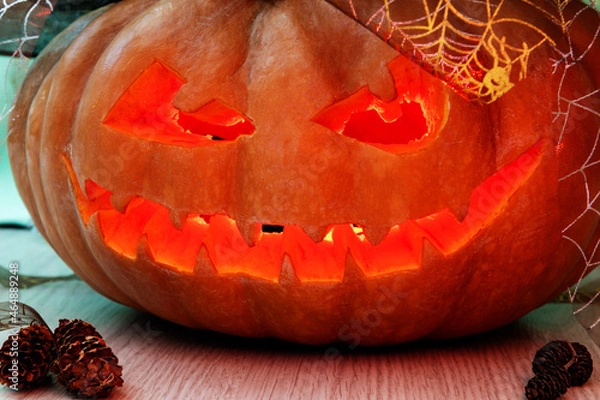 Fototapeta A lantern with a pumpkin head for Halloween, with a candle inside, a dark frightening smile with fangs.