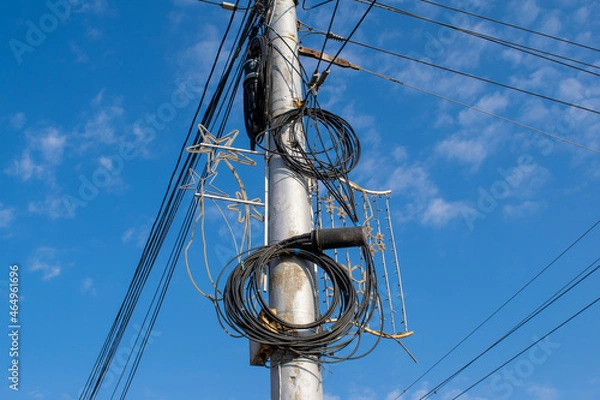 Fototapeta Blue sky background with coils of electrical wires on a street pole against
