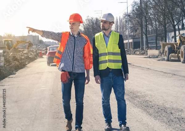 Fototapeta Male workers pouring of concrete pump at construction site. Real Estate Project with Civil Engineer.