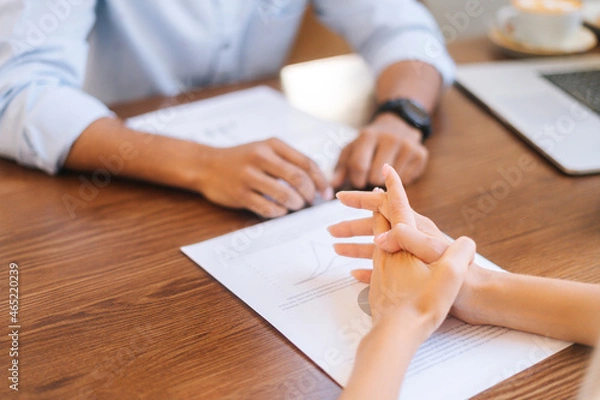 Fototapeta Close-up back view of unrecognizable businesswoman reading documents sitting at table with male business partner in office. Cropped shot of young business team checking data from paper document.