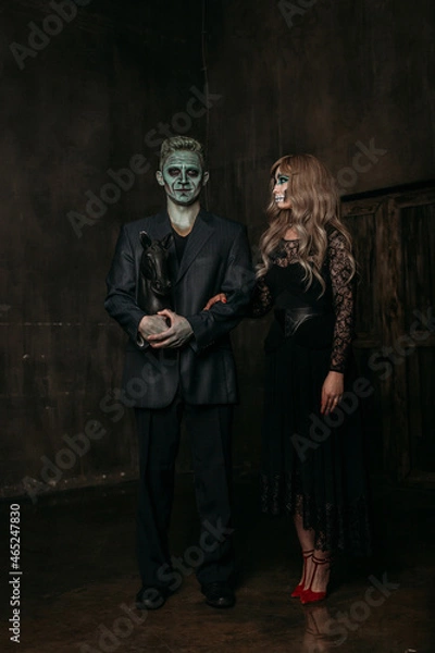 Fototapeta The image of a skeleton girl and the image of a Frankenstein man on Halloween in the dark. an image for a couple on Halloween. they stand next to each other in full height, a woman looks at a man