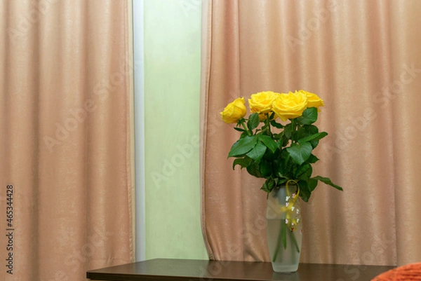 Fototapeta Yellow roses in a vase on the table in the room.