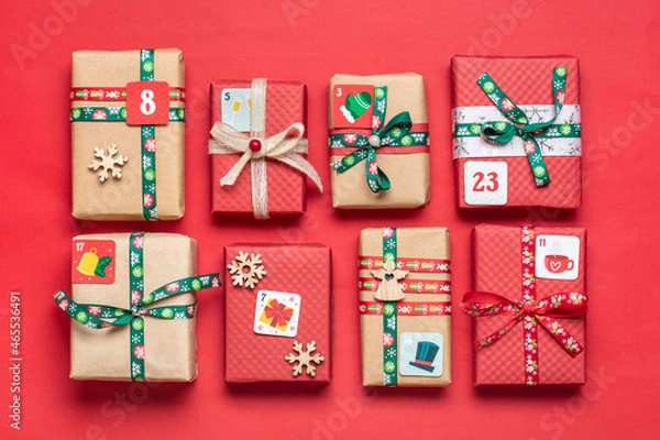 Fototapeta Handmade wrapped red, green gift boxes decorated with ribbons, snowflakes and numbers, Christmas decorations and decor on table Xmas advent calendar concept Top view Flat lay Holiday card