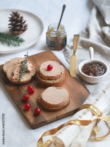 Fototapeta Selective focus of tradtional French foie gras and toaster bread on a wooden plate with Christmas decoration aside with onion marmalade for a festive celebrate.