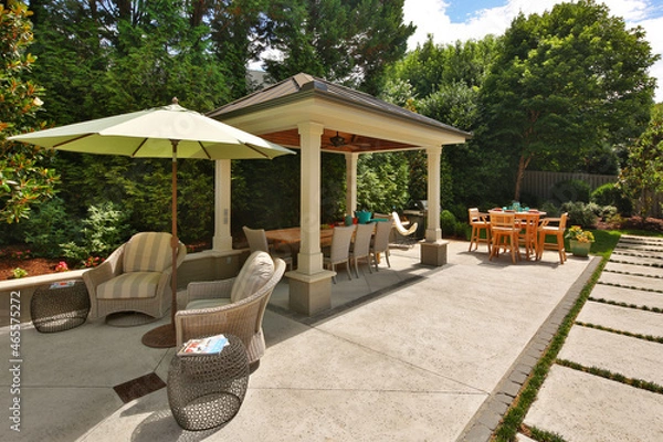 Fototapeta Backyard garden gazebo, table and chairs, umbrella, and stone path