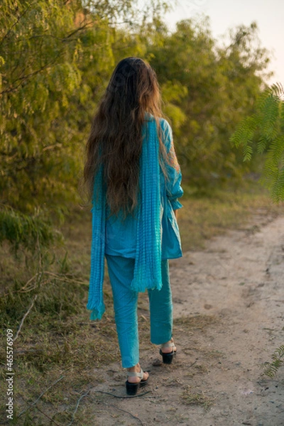 Obraz Girl in Pakistani dress walking on a path surrounded by greenery 