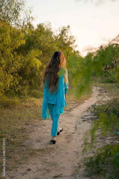 Obraz Girl in Pakistani dress walking on a path surrounded by greenery 