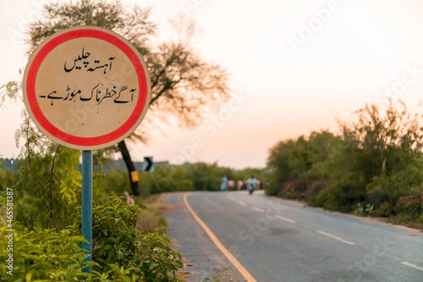 Obraz Sign board in Urdu language to slow down the traffic before sharp turn 