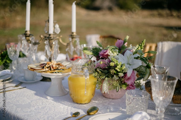 Obraz Table with fresh orange juice in a jug, breakfast in the garden.