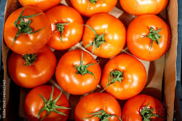 Obraz red tomatoes with green leaves in a box. they are on the shelf of the store. Close-up, top view, food wallpaper.