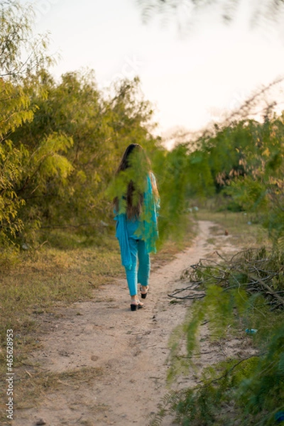 Obraz Girl in Pakistani dress walking on a path surrounded by greenery