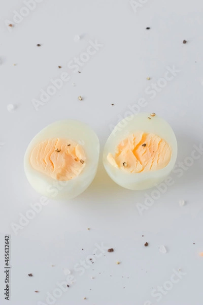 Fototapeta Two halves of a boiled egg on a light background.