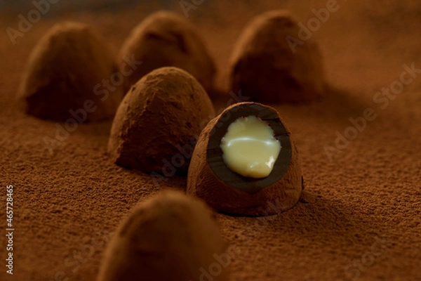 Obraz Truffles with cocoa, coconut and sesame seeds with chocolate with cocoa powder, delicious dessert under dramatic lighting